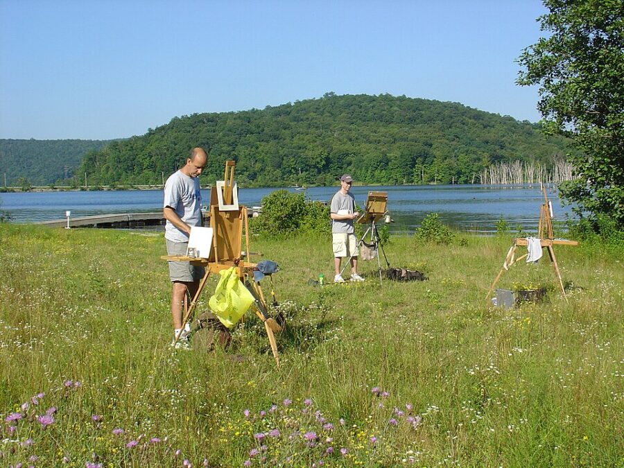 Group of plein air painters working beside a pond